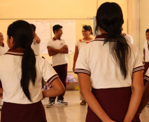 Fotografía donde aparecen jóvenes de secundaria parado en círculo en un salón de clases.