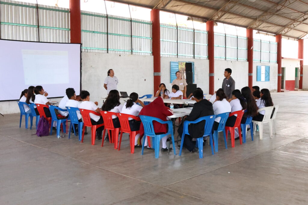 Jóvenes de secundaria sentados en círculo, pretando atención a un tallerista.