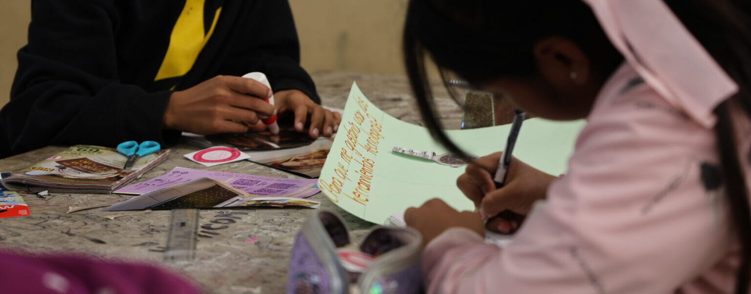 Dos jóvenes adolescentes haciendo un collage sobre violencia digital.