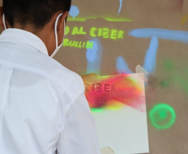 Adolescente pintando con aerosol sobre papel craft