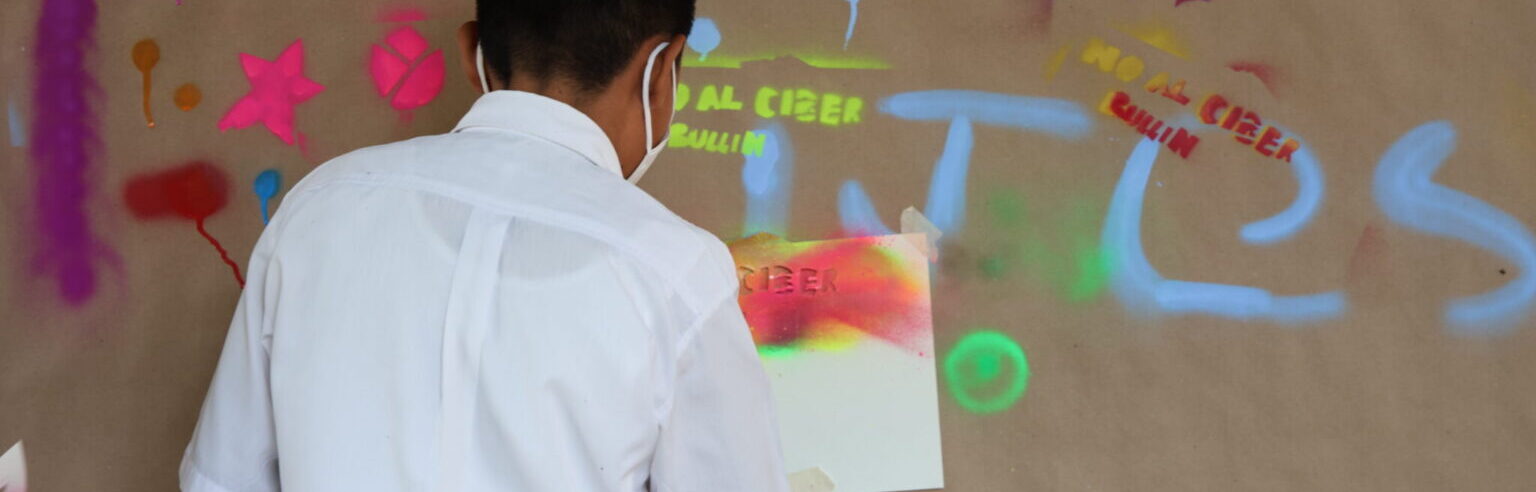 Adolescente pintando con aerosol sobre papel craft