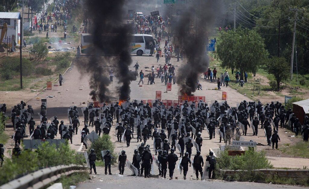 multitud frente a escudos humeantes