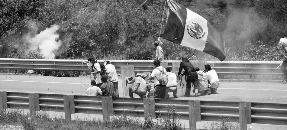 grupo de hombres que esquivan disparos y sostienen una bandera mexicana