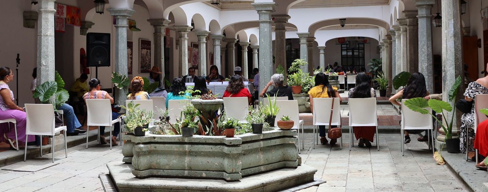 personas sentadas hablando, en el patio de la biblioteca Margharita Maza